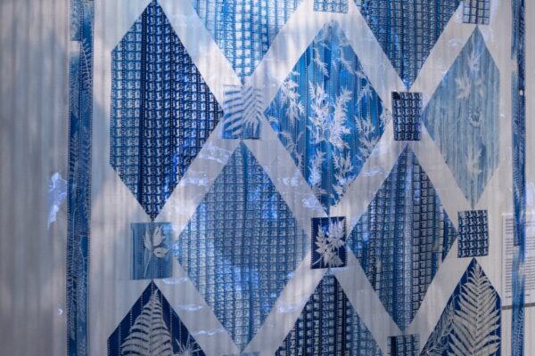 Close up photo of an artwork that is blue and white- woven film into a quilt