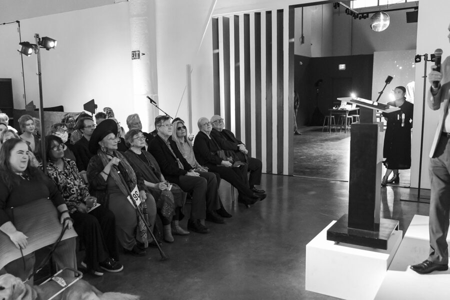 person on a platform talking into a microphone in front of a group of people